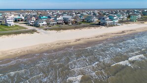 A coastal residential area with houses along the beach, featuring a sandy shoreline and ocean waves.