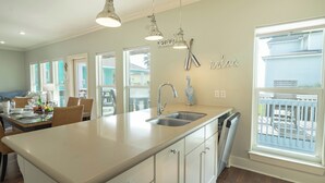 A kitchen with a large island, white cabinetry, a double sink, and pendant lighting.