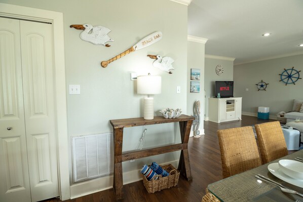 A dining area with a wooden table, wicker chairs, a wall-mounted lamp, and nautical-themed wall decorations. - Changes in Latitudes: 2nd Row Gulf Views / 4BR, Sleeps 14 (Crystal Beach)