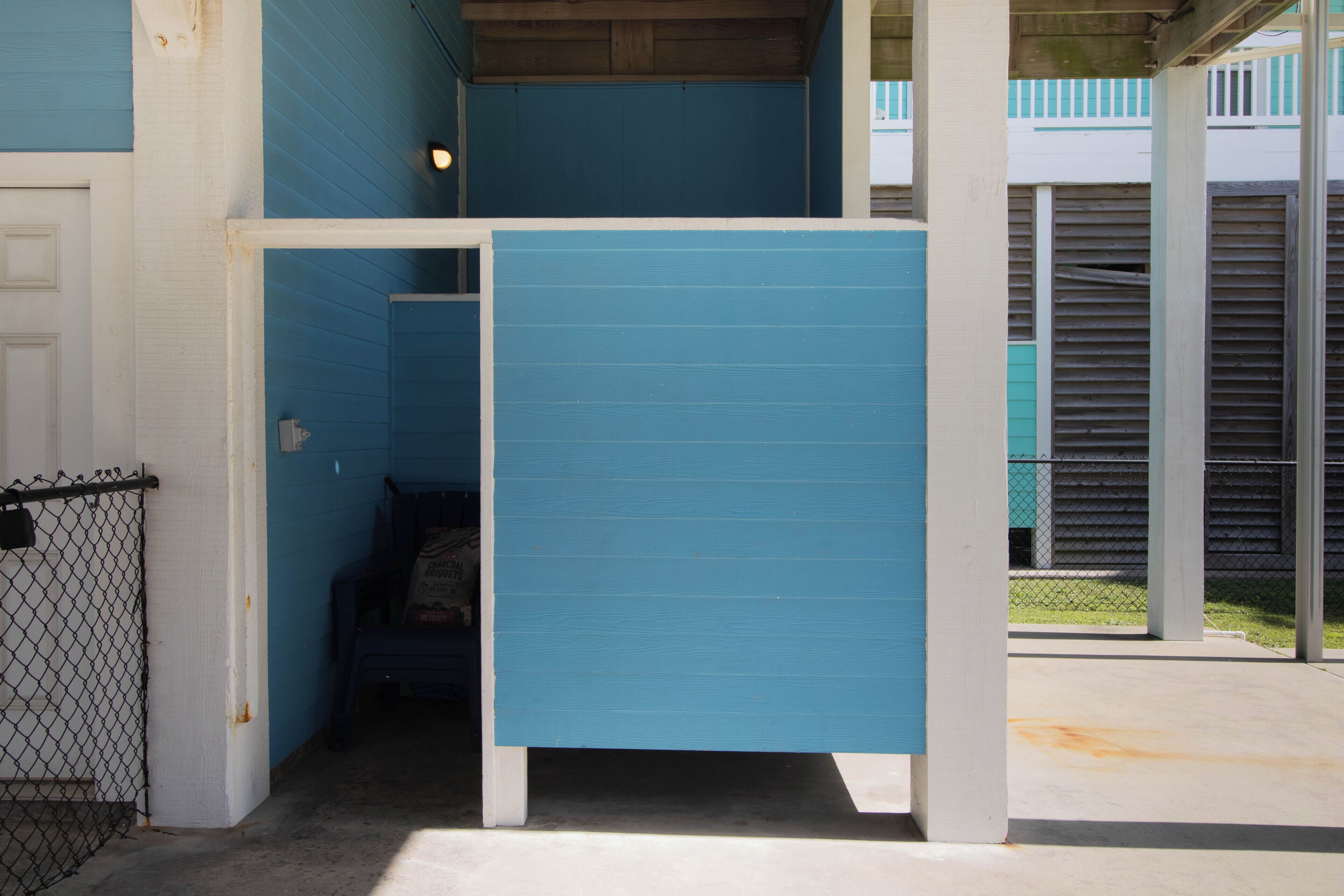 A blue partitioned room with a door, a chain-link fence, and a concrete floor.