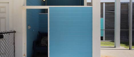 A blue partitioned room with a door, a chain-link fence, and a concrete floor.