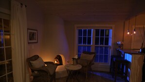 Een gezellige woonkamer met rieten meubels, een open haard en uitzicht op buiten.