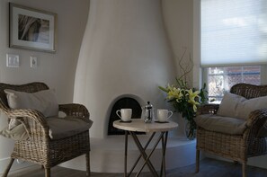 Una habitación acogedora con muebles de mimbre, chimenea y vistas a través de una ventana.