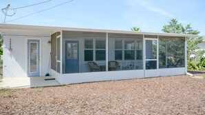 A single-story house with a covered porch, a door, and a small front yard with mulch.