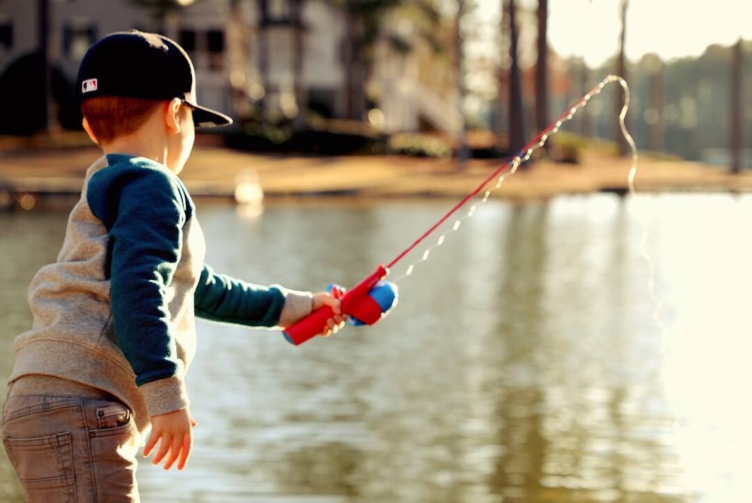 A child fishing by a calm body of water.