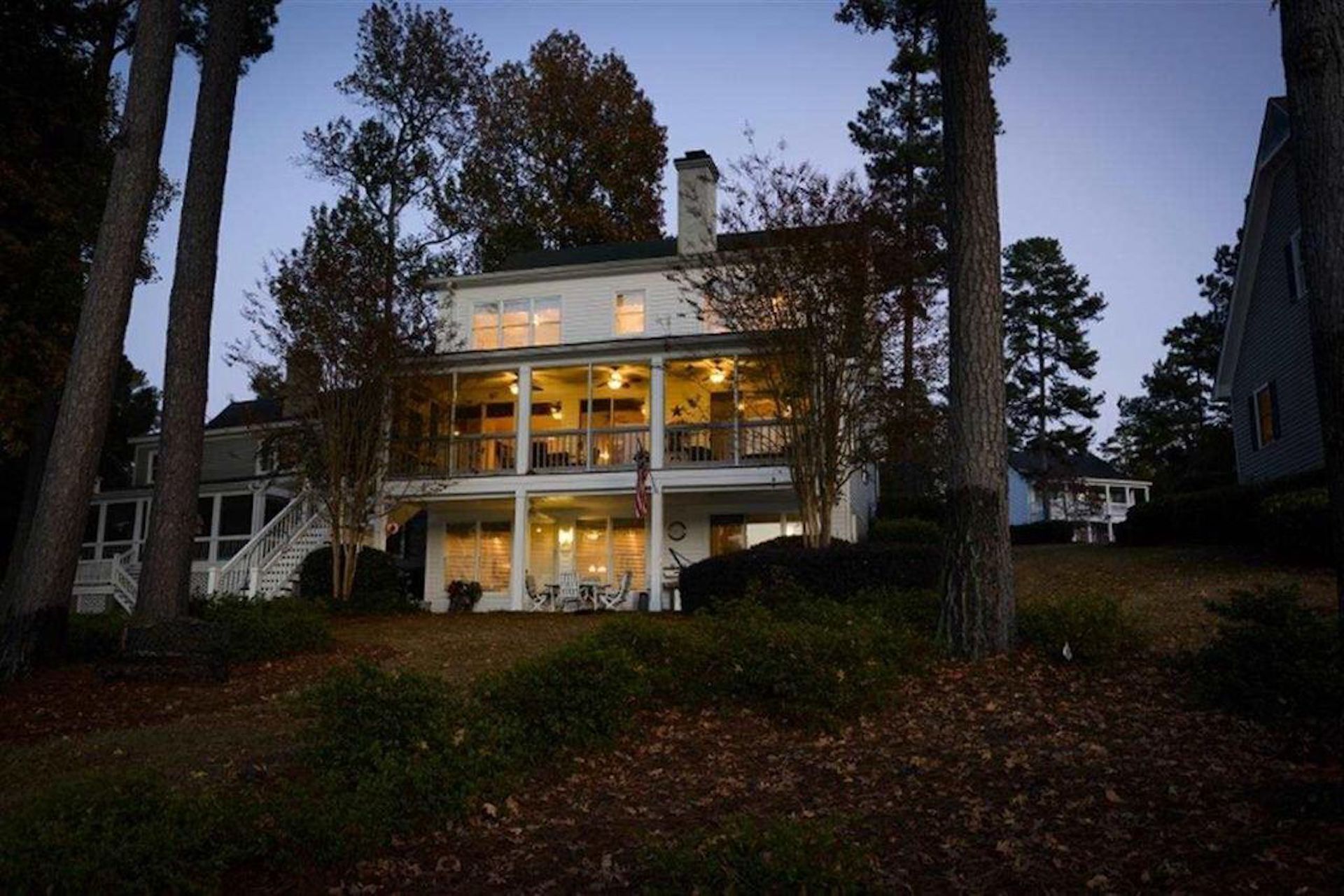 A two-story house with a porch, surrounded by trees.