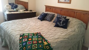 A neatly made bed with a quilt, pillows, and a colorful crocheted throw.