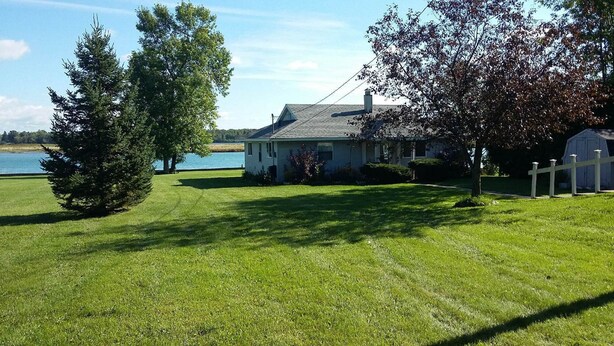 A house with a lawn and a body of water in the background.