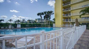 Relax by the pool surrounded by the hotel's architecture and lush palm trees.