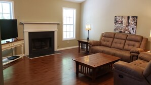 A living room with a fireplace, a sofa, a coffee table, and two lamps. - SPACIOUS Cartersville HOME that SLEEPS UP TO 13 PEOPLE and 12 min. to Lakepoint! (Cartersville)