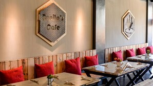 A restaurant interior with wooden tables and benches, red cushions, and a wall sign reading "Donito's Cafe". - Bhive Hotel (Iloilo)