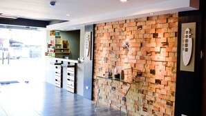 A modern interior with a brick wall, a glass display case, and a kitchen area. - Bhive Hotel (Iloilo)