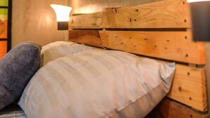A bedroom with a wooden headboard, two bedside lamps, and a wall-mounted hexagonal light fixture. - Bhive Hotel (Iloilo)