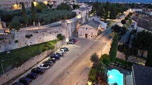 Un pueblo histórico con edificios de piedra, un estacionamiento y vistas a montañas distantes.