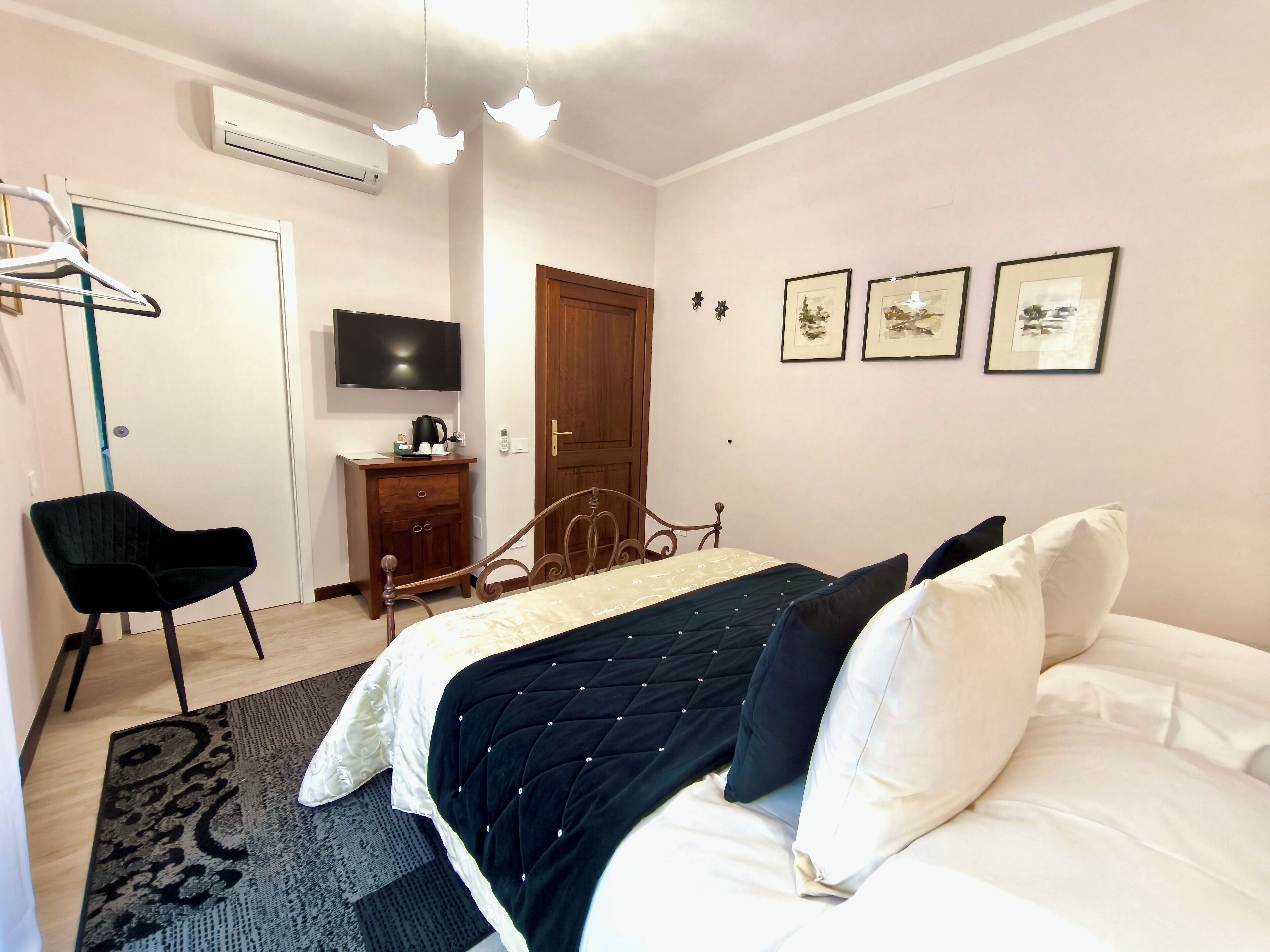 A bedroom with a bed, a chair, a dresser, a television, and framed pictures on the wall.