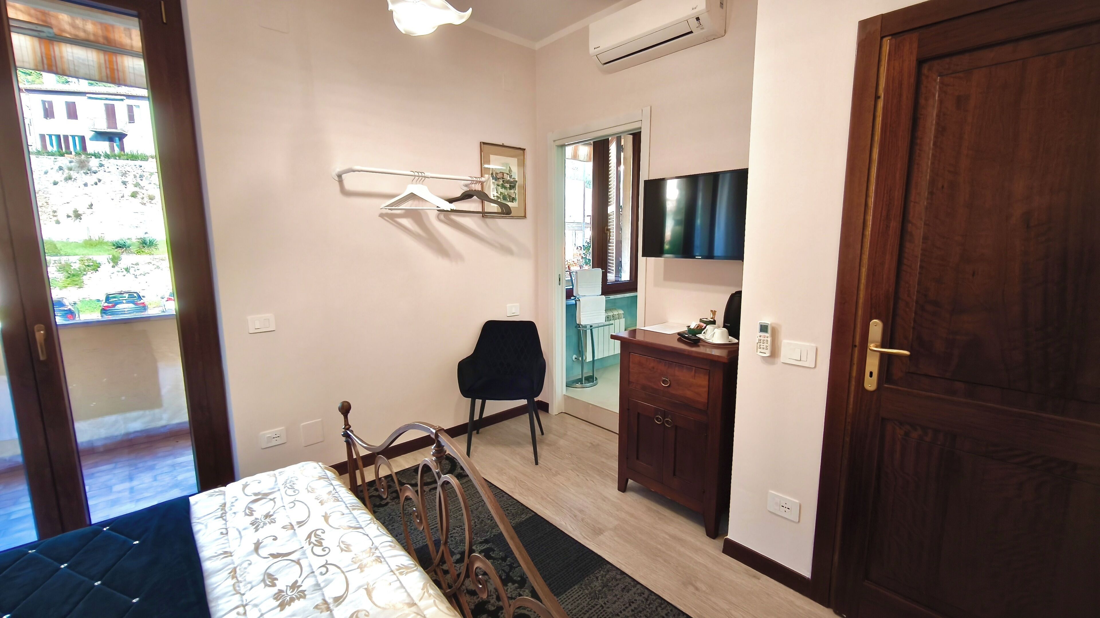 A small, well-lit room with a bed, a chair, a dresser, and a television.