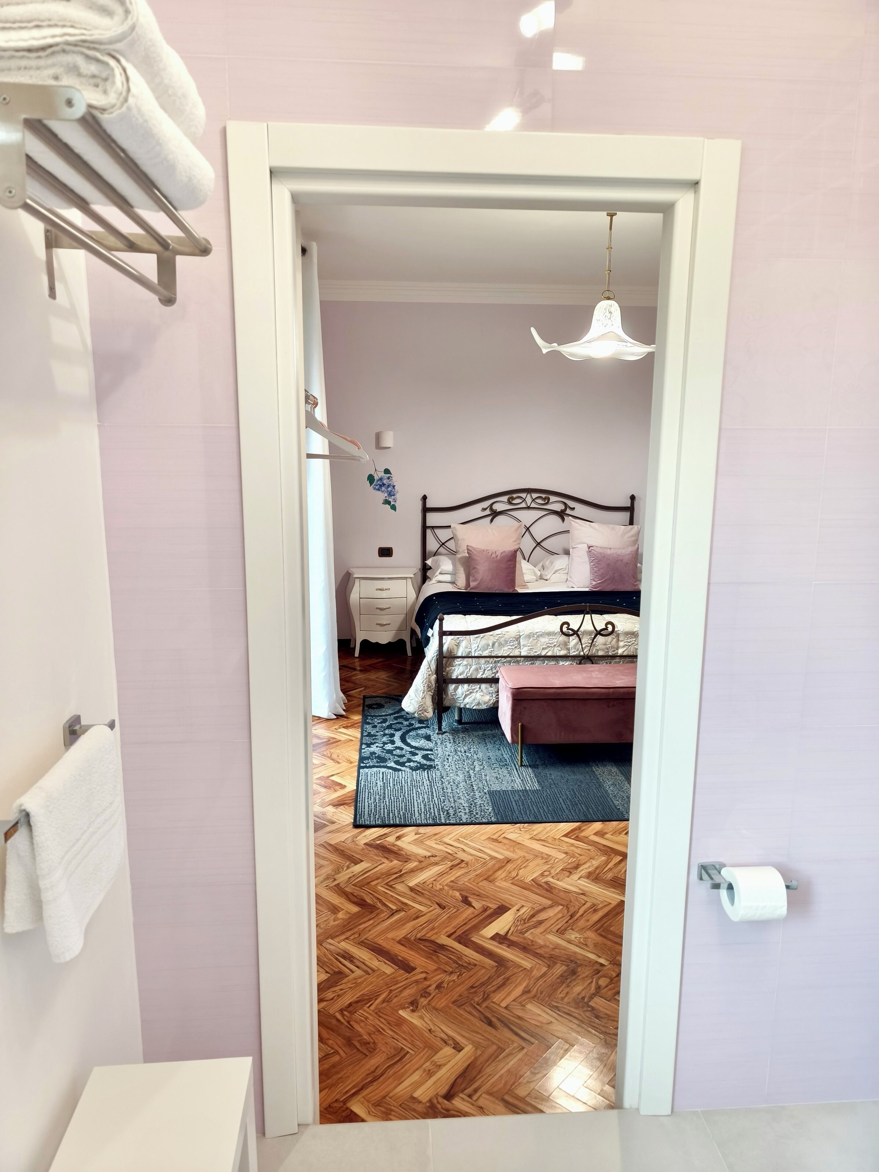 A bedroom with a bed, bedside table, and a hanging light fixture.