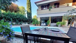 Un patio con mesa y sillas, una piscina y un edificio con balcones.