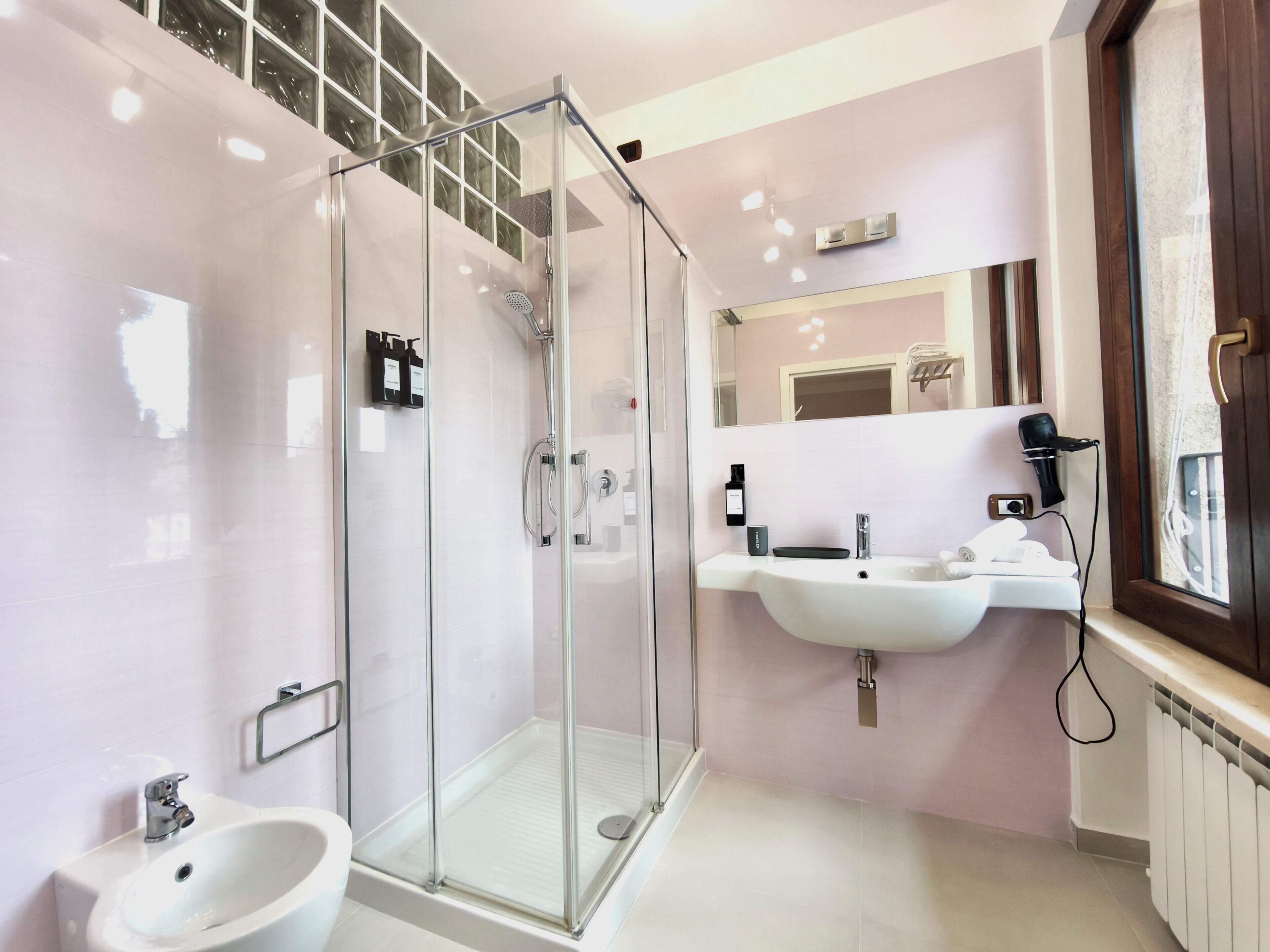 A modern bathroom with a glass-enclosed shower, a sink, and a bidet.