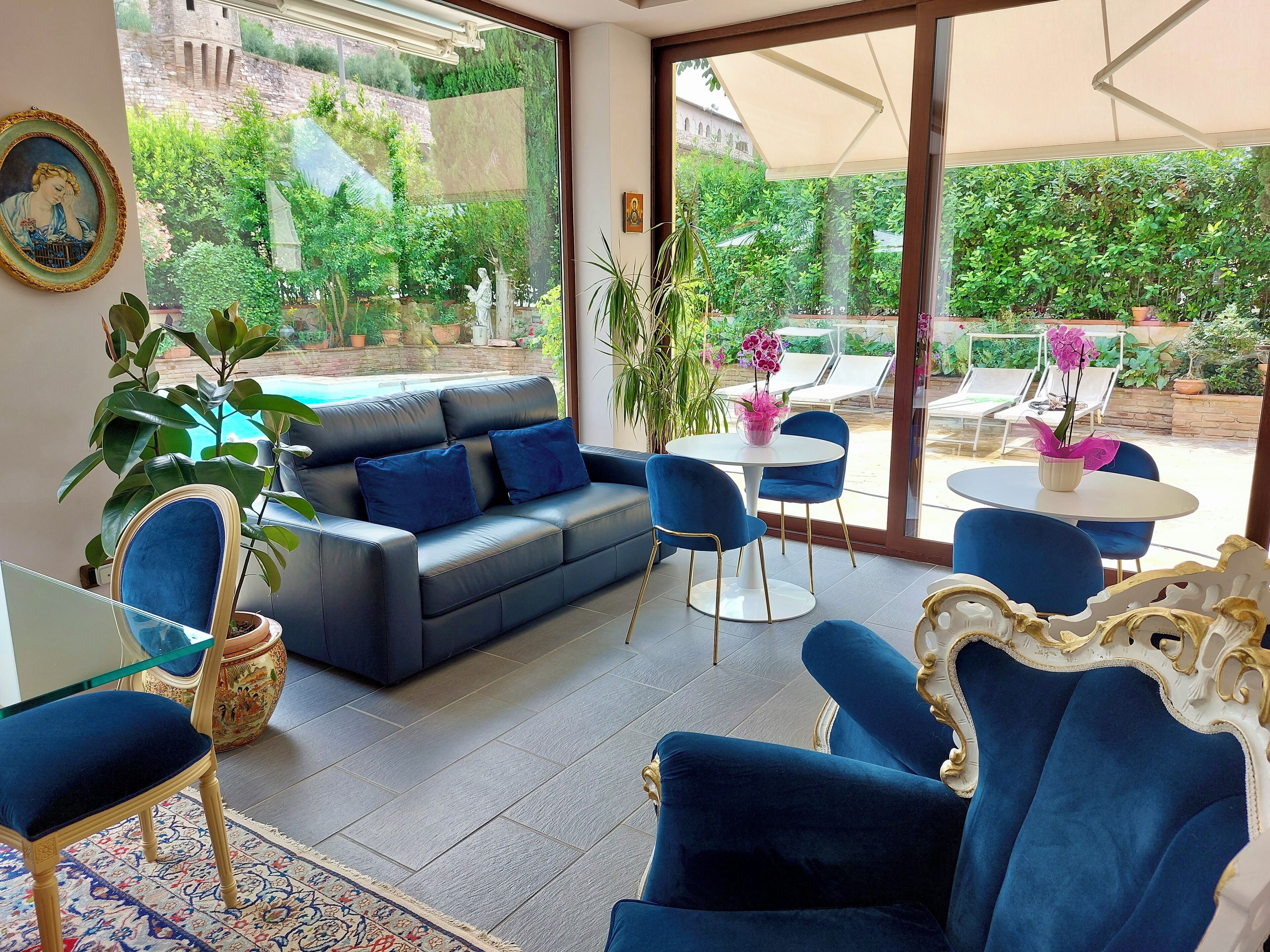 Un espace de détente moderne avec un canapé en cuir, des fauteuils bleus et une table en verre.