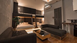 Une pièce compacte et moderne, dotée de lits superposés, d’un canapé, d’une table basse et d’un petit coin cuisine.