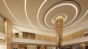 A spacious lobby with a central column, a staircase, and a reception area.
