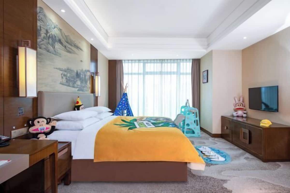Ein Hotelzimmer mit Bett, Schreibtisch, Fernseher und einem großen Gemälde an der Wand.