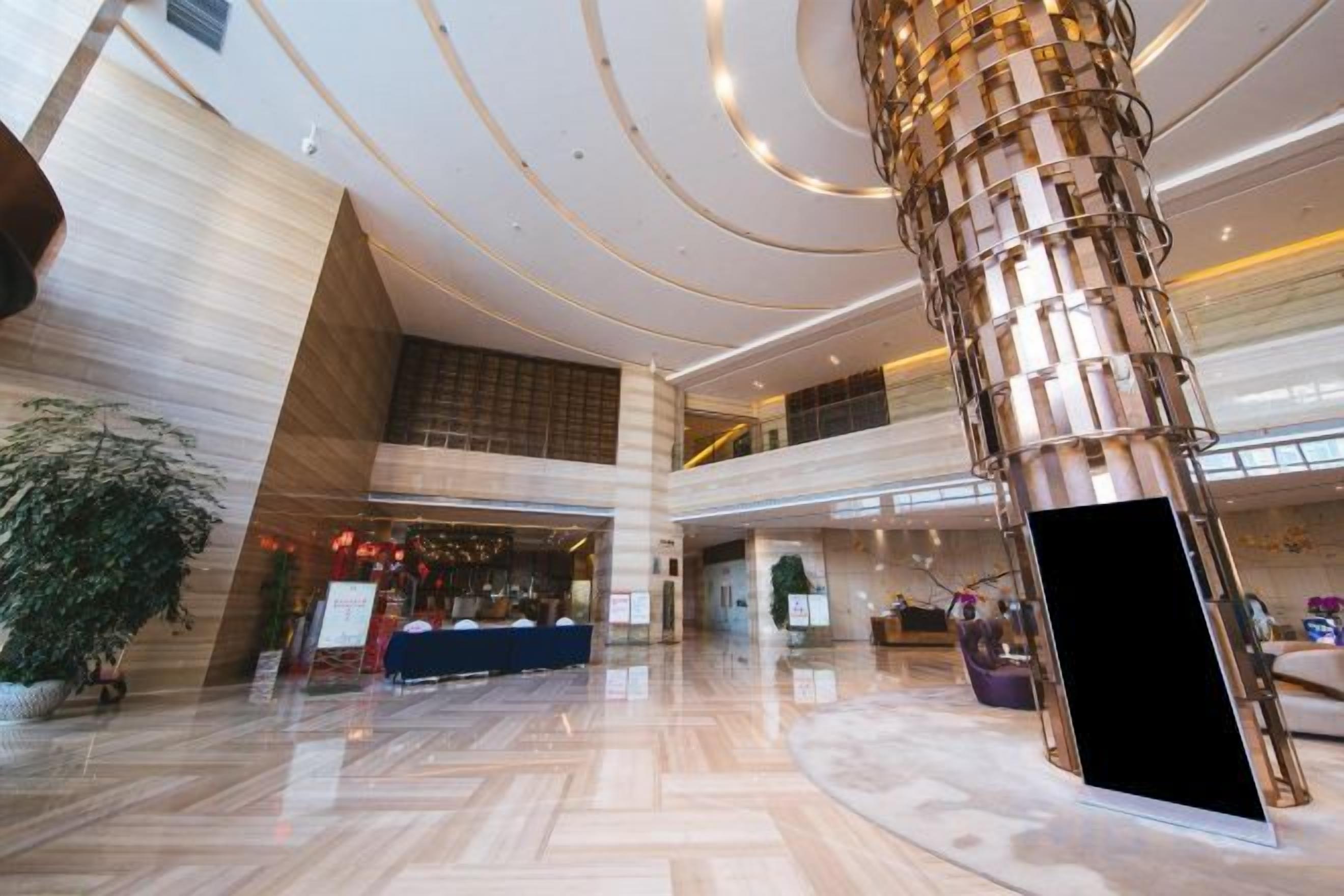 A spacious lobby with a high ceiling, a central column, and a reception desk.