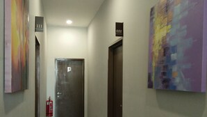 Un pasillo con dos puertas, una con el número 111 y otra con el 222, y un extintor en la pared izquierda.