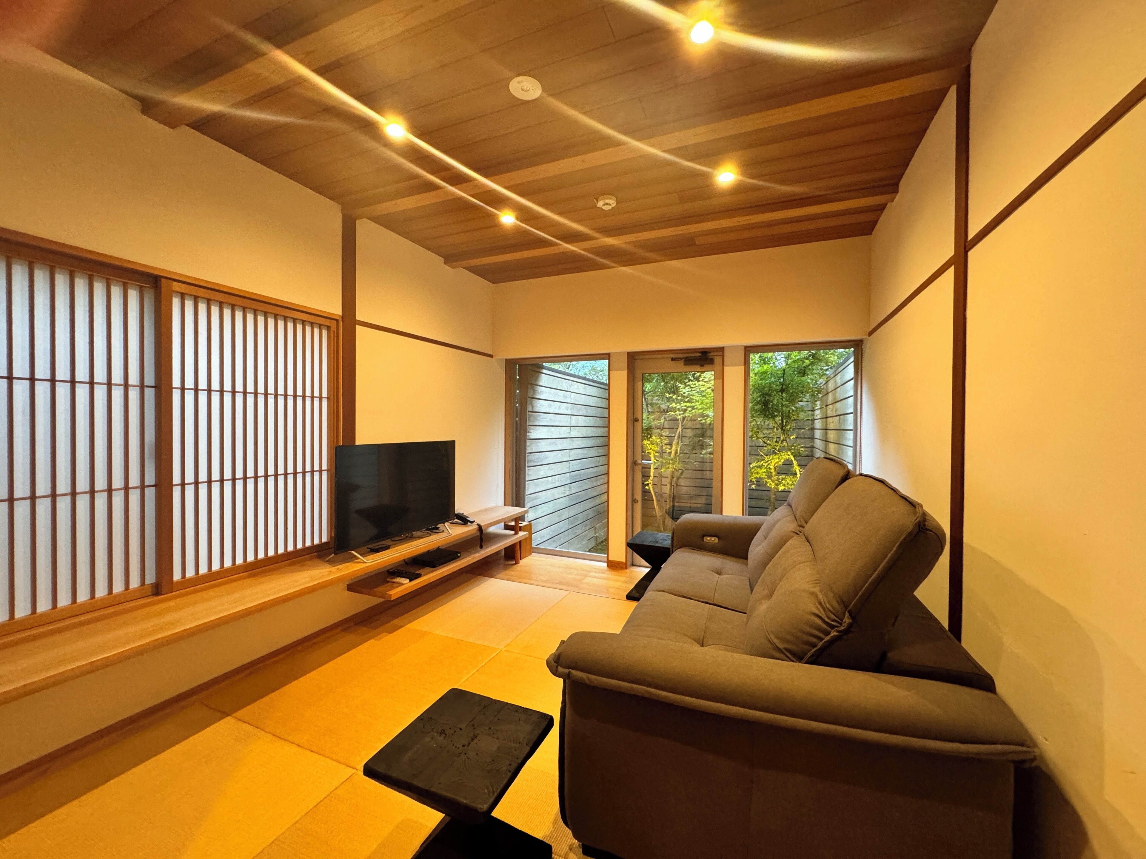 Een moderne woonkamer met een flatscreen televisie, een bank en een vloer met tatami matten.