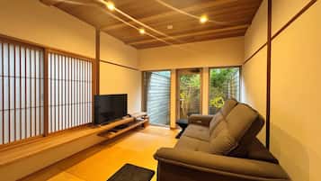 Een moderne woonkamer met een flatscreen televisie, een bank en een vloer met tatami matten.