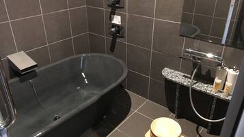 Een moderne badkamer met een vrijstaand bad, toilet en douche.