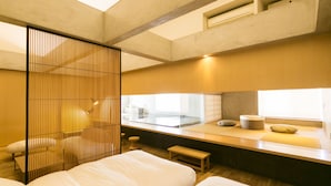 Habitación de hotel moderna con una cama grande, un pequeño rincón de descanso, una ventana con vistas y una puerta corredera.