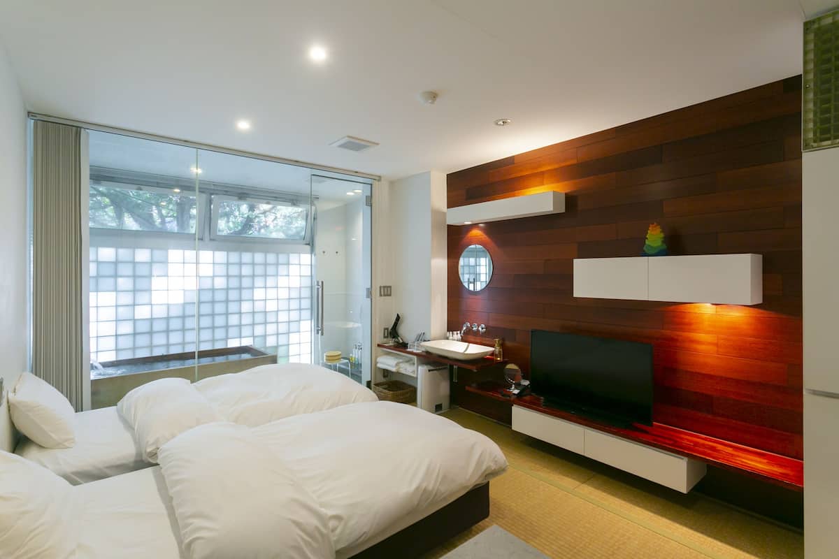 A modern bedroom with a large bed, a TV, and a bathroom with a sink and mirror.