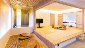Una habitación tradicional japonesa con suelo de tatami, una cama baja y un televisor.