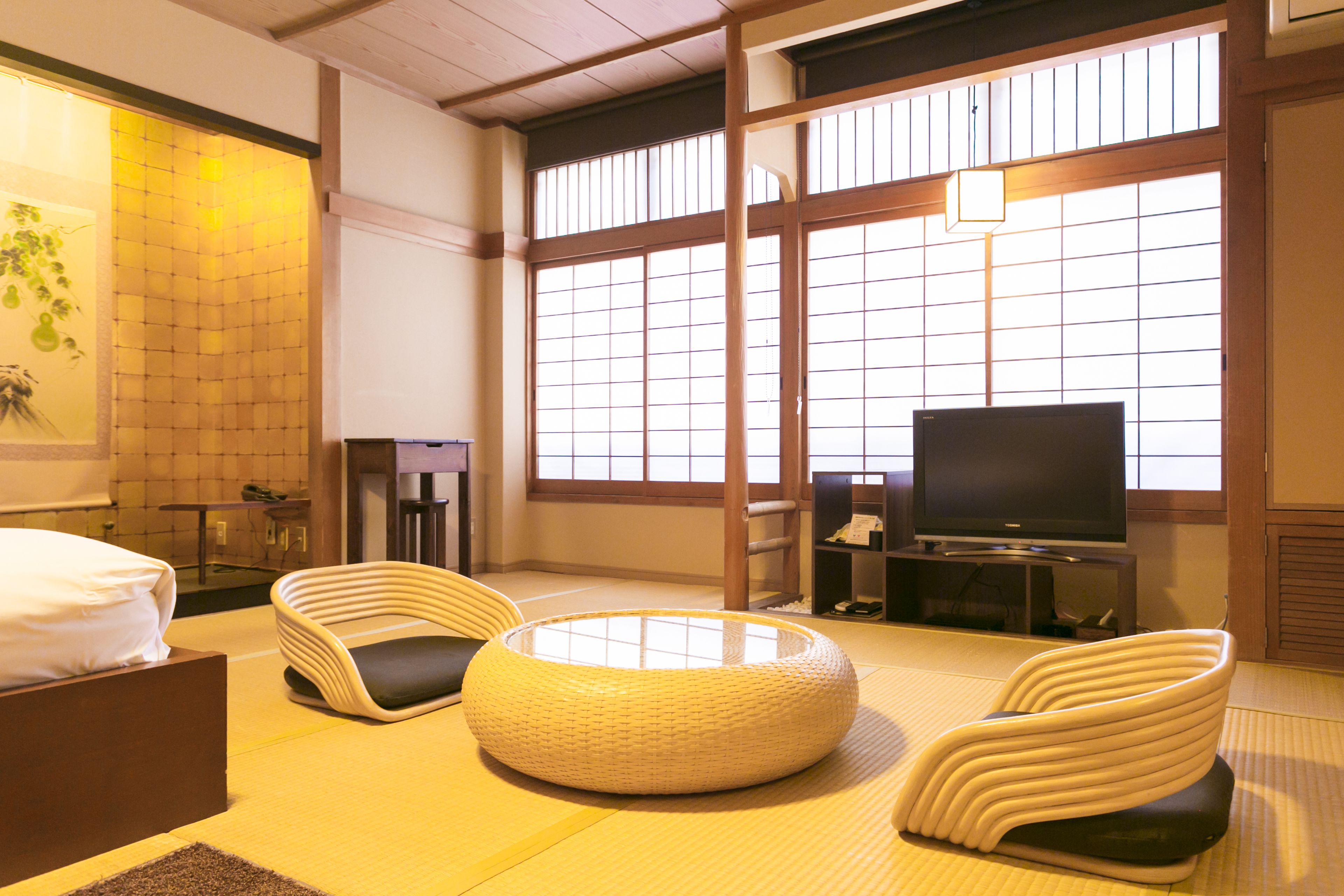 Una habitación de estilo japonés tradicional con suelo de tatami, una mesa baja, un sofá y una televisión.