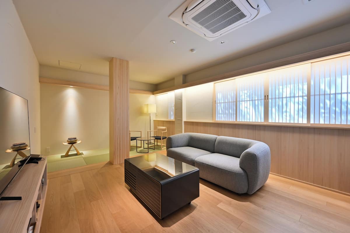 A modern living room with a sofa, a glass coffee table, and a TV.
