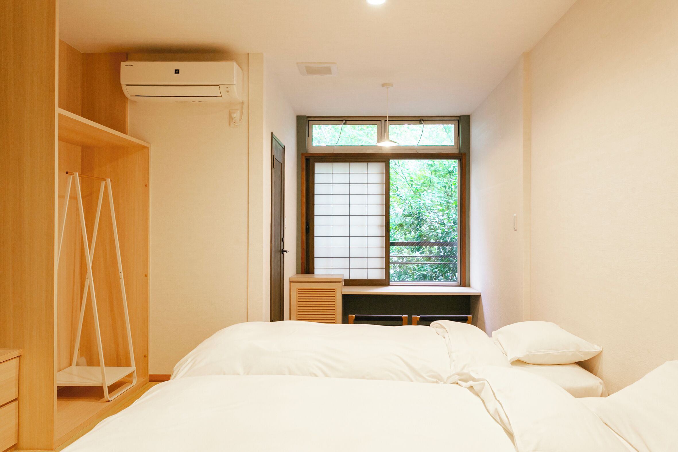 A bedroom with a bed, a desk, and a wardrobe.