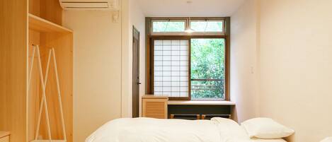 A bedroom with a bed, a desk, and a wardrobe.