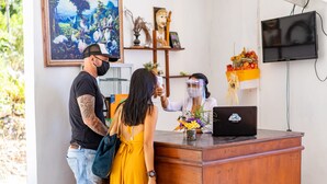 Een receptiebalie met een laptop, een vaas met bloemen en een plank met decoratieve objecten.