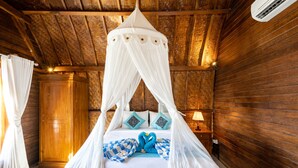 A room with a wooden ceiling, a bed with a canopy, and a nightstand with a lamp. - Sundi Ocean Bungalow by ABM (Penida Island)