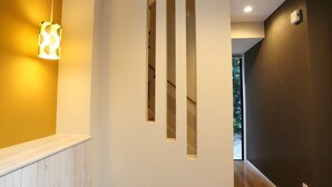 A modern interior with a wooden floor, a staircase with white railings, and a wall-mounted light fixture. - Tabinoteitaku Okinawa Bise Homann Concept (Motobu)