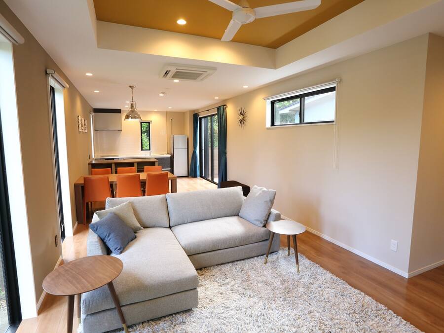 A modern living room with a sectional sofa, a small round table, and a kitchen in the background.
