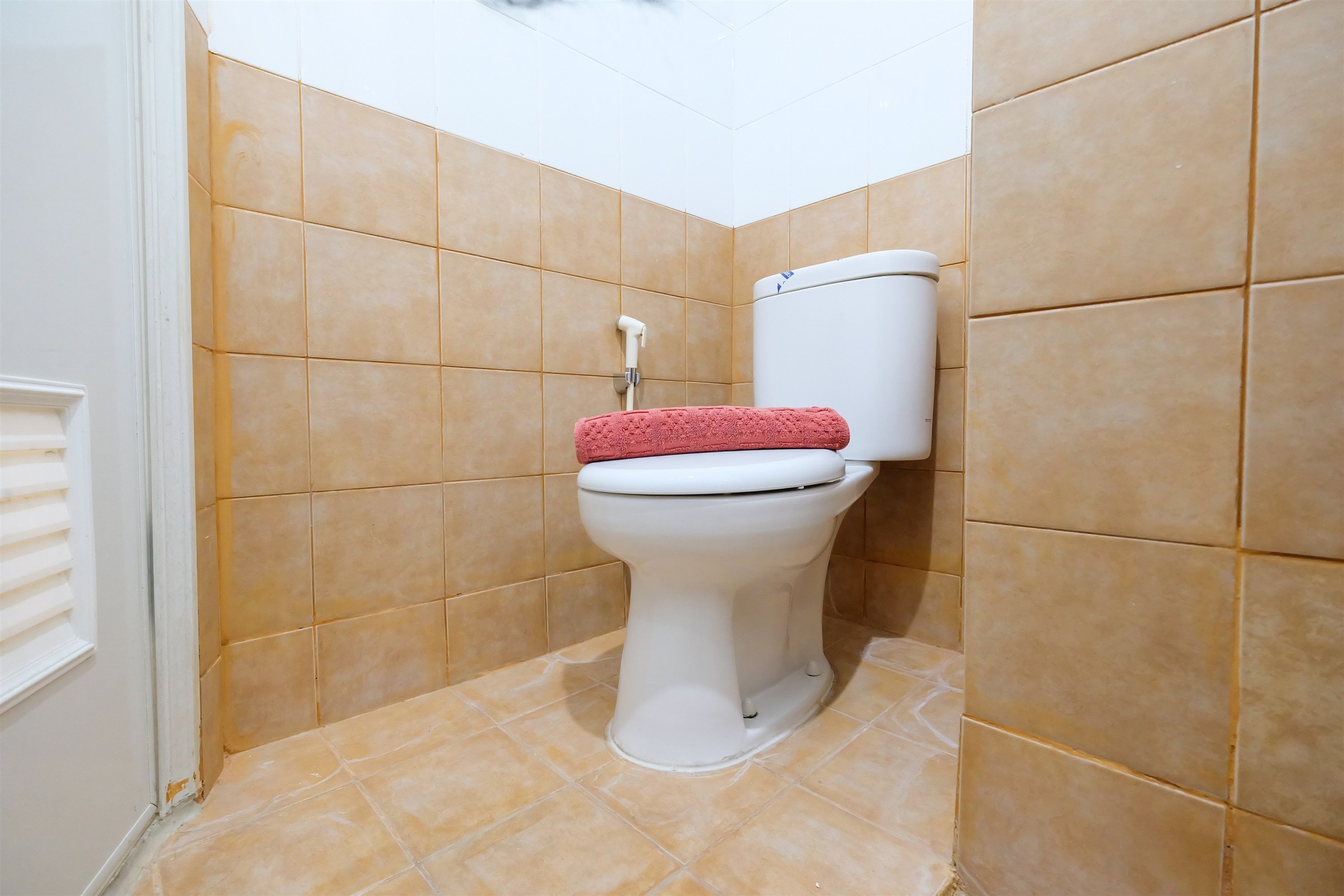 Un bagno con il water, piastrelle color crema e una porta bianca.