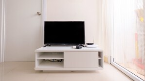 Un mueble de entretenimiento blanco con un televisor de pantalla plana, un control remoto y un router.