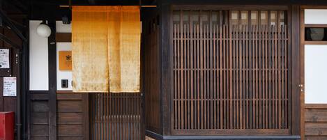 A traditional Japanese building with a wooden entrance, a sliding door, and a tiled ground.