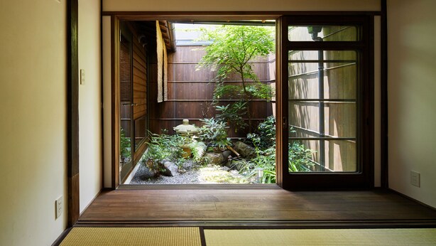 A traditional Japanese interior with tatami flooring, a sliding door leading to a garden view, and a shoji screen. - Tachibana an (Kyoto)