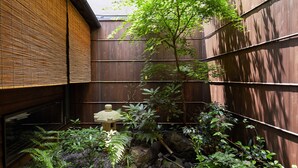 A traditional Japanese garden with a wooden fence, a stone lantern, and various plants. - Tachibana an (Kyoto)