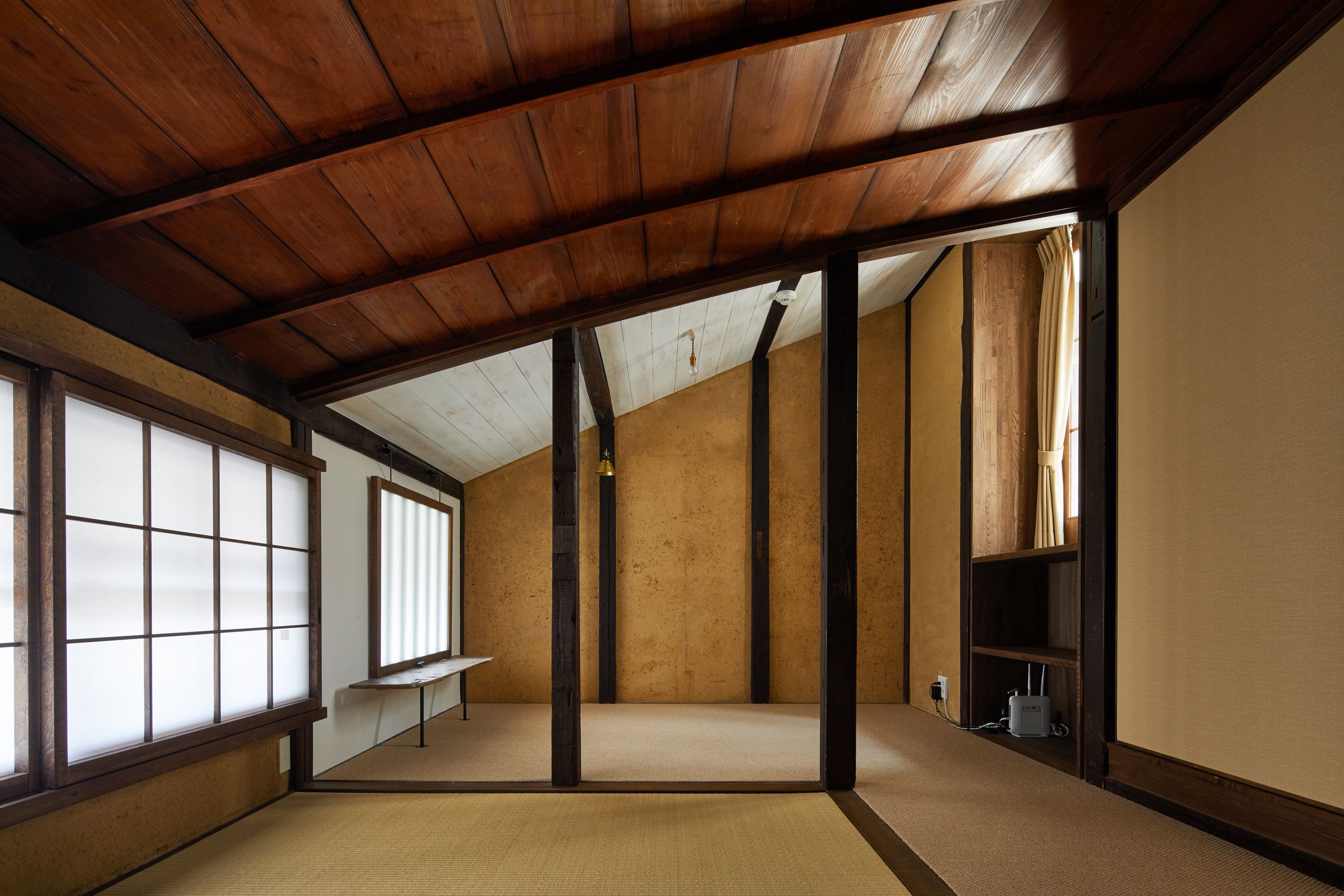 Ein traditioneller japanischer Raum mit Tatami-Böden, Holzbalken und Schiebetüren.