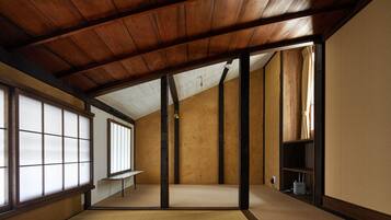 Ein traditioneller japanischer Raum mit Tatami-Böden, Holzbalken und Schiebetüren.